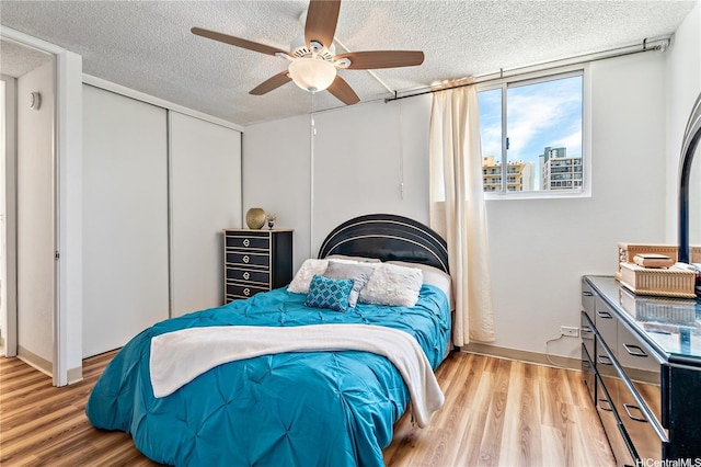 2452 Tusitala St Unit 705, Honolulu, HI 96815 - bedroom with light wood-style floors, a textured ceiling, a closet, a ceiling fan, and baseboards