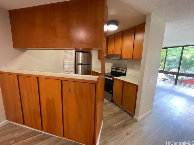 1441 Piikoi St Unit 402, Honolulu, HI 96822 - kitchen with appliances with stainless steel finishes, light wood finished floors, brown cabinets, light countertops, and under cabinet range hood
