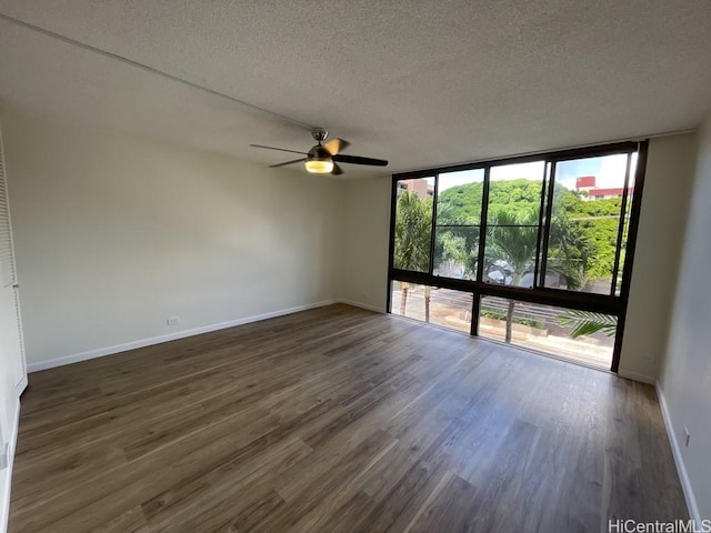 1441 Piikoi St Unit 402, Honolulu, HI 96822 - unfurnished room with a wall of windows, a textured ceiling, baseboards, dark wood-style floors, and a ceiling fan