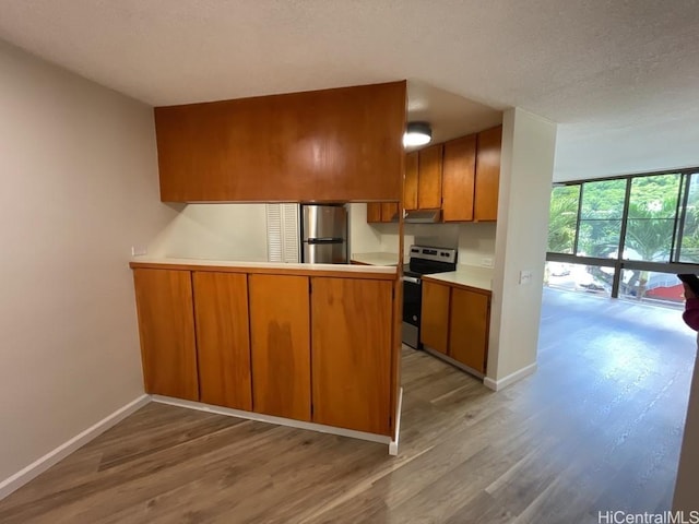 1441 Piikoi St Unit 402, Honolulu, HI 96822 - kitchen featuring stainless steel appliances, brown cabinetry, light wood finished floors, a peninsula, and baseboards