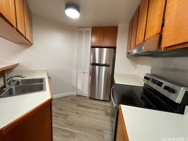 1441 Piikoi St Unit 402, Honolulu, HI 96822 - kitchen featuring appliances with stainless steel finishes, a sink, under cabinet range hood, brown cabinetry, and light countertops