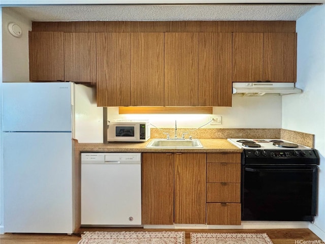 1655 Makaloa St Unit 705, Honolulu, HI 96814 - kitchen with white appliances, a sink, under cabinet range hood, light countertops, and wood finished floors