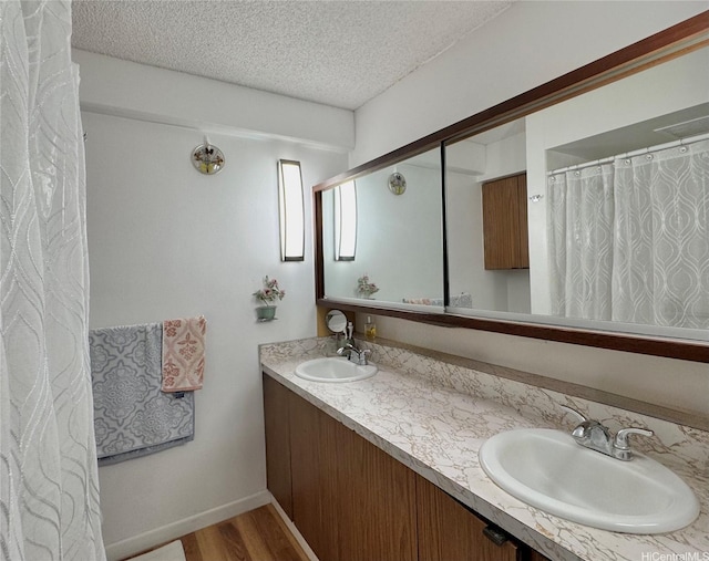 1655 Makaloa St Unit 705, Honolulu, HI 96814 - bathroom with a textured ceiling, wood finished floors, double vanity, and baseboards