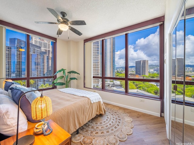 725 Kapiolani Blvd Unit 1105, Honolulu, HI 96813 - bedroom featuring baseboards, wood finished floors, multiple windows, a textured ceiling, and a city view