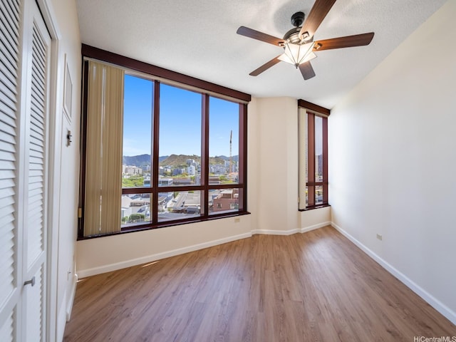 725 Kapiolani Blvd Unit 1105, Honolulu, HI 96813 - unfurnished room featuring wood finished floors, a mountain view, a ceiling fan, and baseboards