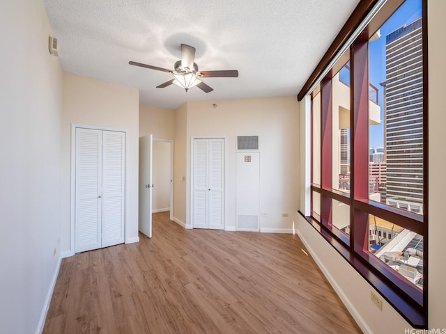 725 Kapiolani Blvd Unit 1105, Honolulu, HI 96813 - unfurnished bedroom with wood finished floors, baseboards, a textured ceiling, two closets, and ceiling fan