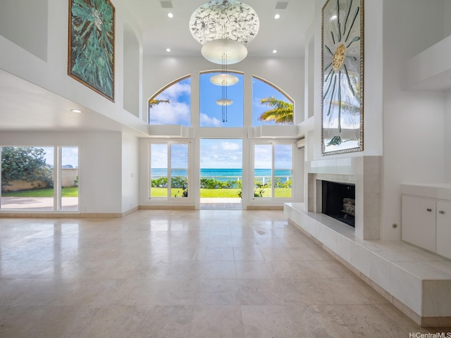 756 Mokulua Dr, Kailua, HI 96734 - unfurnished living room with a towering ceiling, a tiled fireplace, recessed lighting, and a water view