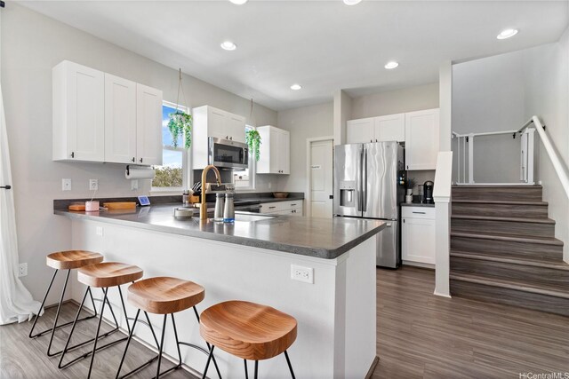 91-1123 Hokua St, Ewa Beach, HI 96706 - kitchen featuring stainless steel appliances, a peninsula, a kitchen breakfast bar, dark countertops, and white cabinets