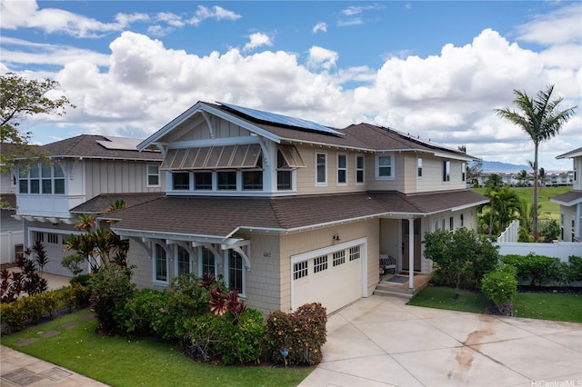 91-1124 Kai Oio St, Ewa Beach, HI 96706 - view of front of home featuring an attached garage, roof mounted solar panels, a shingled roof, board and batten siding, and driveway
