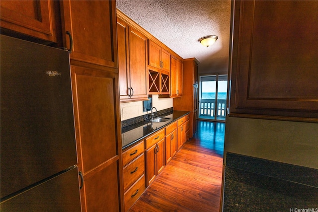 84-965 Farrington Hwy Unit B216, Waianae, HI 96792 - kitchen featuring freestanding refrigerator, light wood finished floors, a sink, a textured ceiling, and dark stone countertops