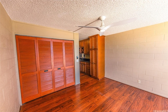 84-965 Farrington Hwy Unit B216, Waianae, HI 96792 - unfurnished bedroom featuring dark wood-style floors, a closet, a textured ceiling, concrete block wall, and ceiling fan