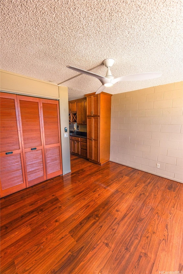 84-965 Farrington Hwy Unit B216, Waianae, HI 96792 - unfurnished living room featuring dark wood-style flooring, concrete block wall, and a textured ceiling