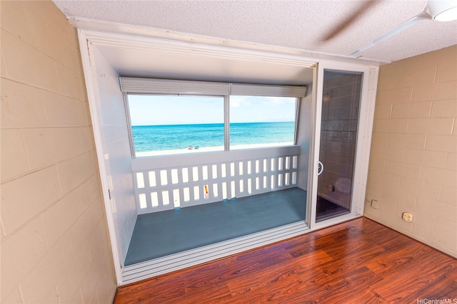 84-965 Farrington Hwy Unit B216, Waianae, HI 96792 - empty room featuring concrete block wall, wood finished floors, a water view, and a textured ceiling