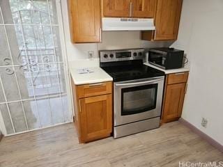 2123 Wilson St, Honolulu, HI 96819 - kitchen featuring stainless steel electric range, under cabinet range hood, brown cabinetry, light wood-style floors, and baseboards