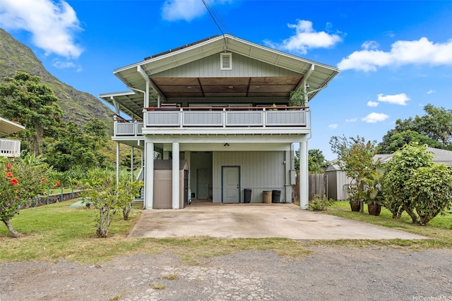 51-17 Kaaawa Pl, Kaaawa, HI 96730 - view of front facade with a balcony, dirt driveway, a mountain view, and a carport