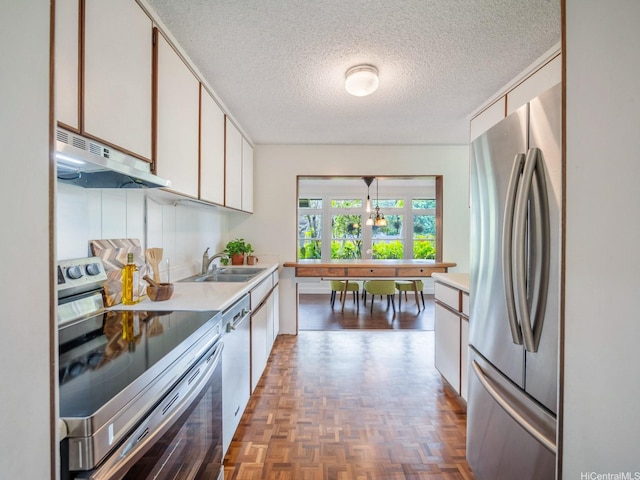 1257 Maleko St, Kailua, HI 96734 - kitchen with appliances with stainless steel finishes, under cabinet range hood, a sink, a textured ceiling, and white cabinetry