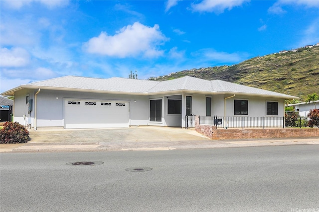 ranch-style home featuring stucco siding, a garage, driveway, a mountain view, and a porch