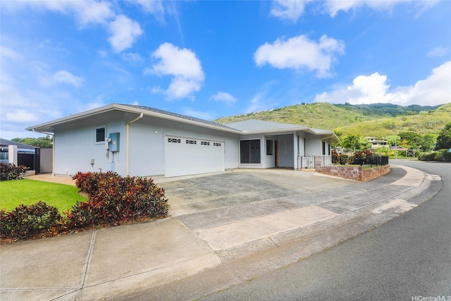 single story home with a garage, stucco siding, concrete driveway, and a mountain view