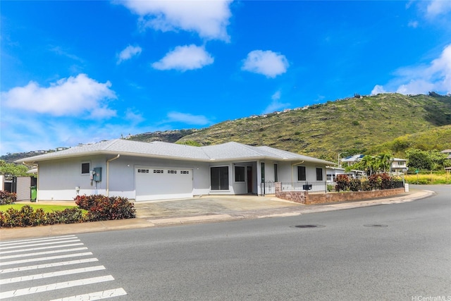 single story home with a garage, stucco siding, concrete driveway, and a mountain view