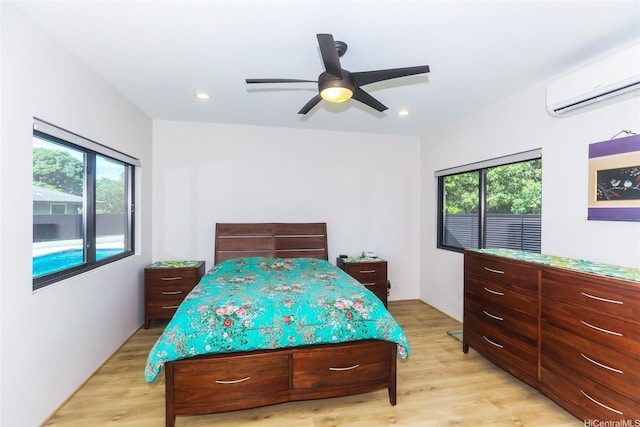 bedroom featuring a wall unit AC, light wood-type flooring, recessed lighting, and ceiling fan