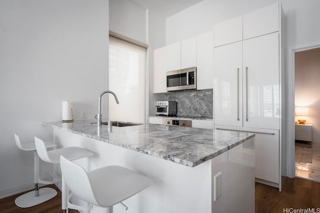 987 Queen St Unit 814, Honolulu, HI 96814 - kitchen featuring a sink, stainless steel microwave, paneled refrigerator, a kitchen breakfast bar, and white cabinets