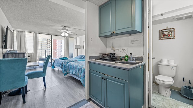 445 Seaside St Unit 1205, Honolulu, HI 96815 - kitchen featuring a sink, a ceiling fan, a textured ceiling, light wood-style floors, and blue cabinets