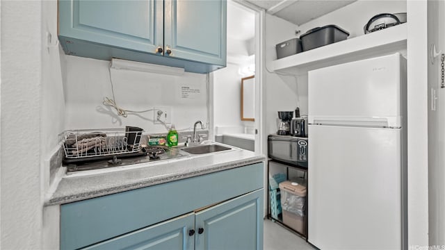 445 Seaside St Unit 1205, Honolulu, HI 96815 - kitchen with freestanding refrigerator, blue cabinets, a sink, and black microwave