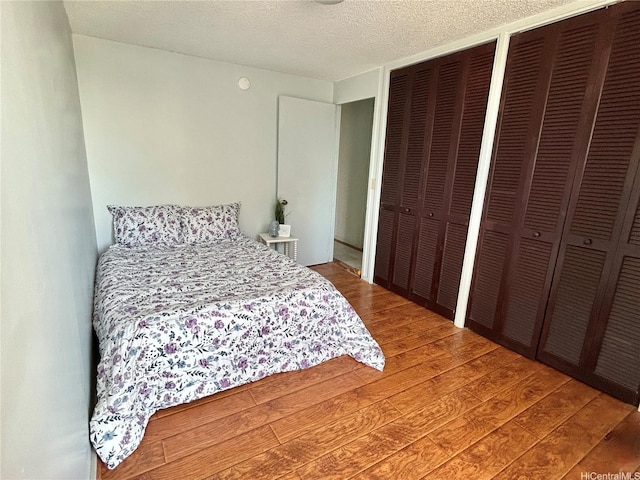 1624 Kanunu St Unit 1208, Honolulu, HI 96814 - bedroom with light wood-type flooring, multiple closets, and a textured ceiling