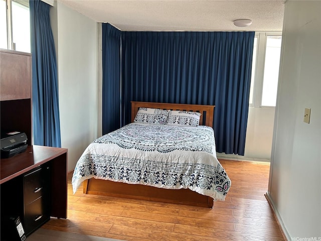 1624 Kanunu St Unit 1208, Honolulu, HI 96814 - bedroom with wood finished floors, multiple windows, a textured ceiling, and baseboards
