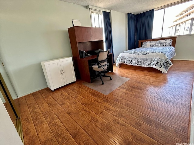 1624 Kanunu St Unit 1208, Honolulu, HI 96814 - bedroom with a textured ceiling, hardwood / wood-style flooring, an office area, and baseboards