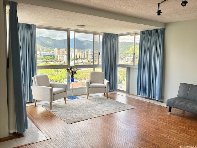1624 Kanunu St Unit 1208, Honolulu, HI 96814 - sitting room featuring expansive windows, a textured ceiling, a mountain view, and wood finished floors