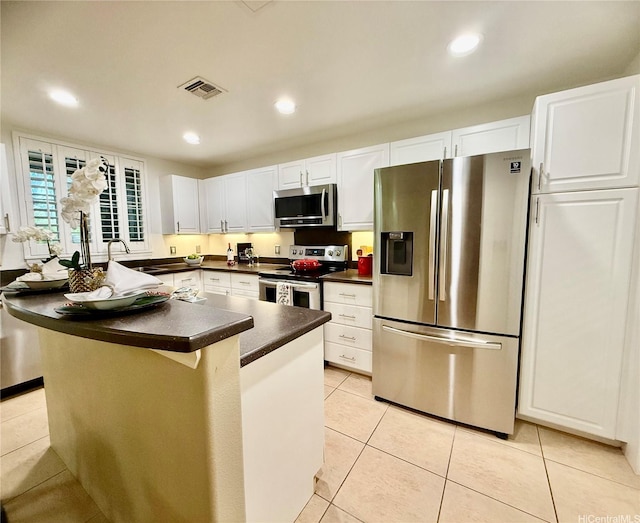 7018 Hawaii Kai Dr Unit 6-12, Honolulu, HI 96825 - kitchen with stainless steel appliances, dark countertops, light tile patterned flooring, white cabinets, and recessed lighting