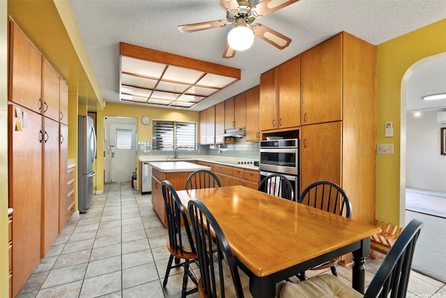 98-042 Puaalii Way, Aiea, HI 96701 - kitchen featuring appliances with stainless steel finishes, arched walkways, brown cabinetry, under cabinet range hood, and light countertops