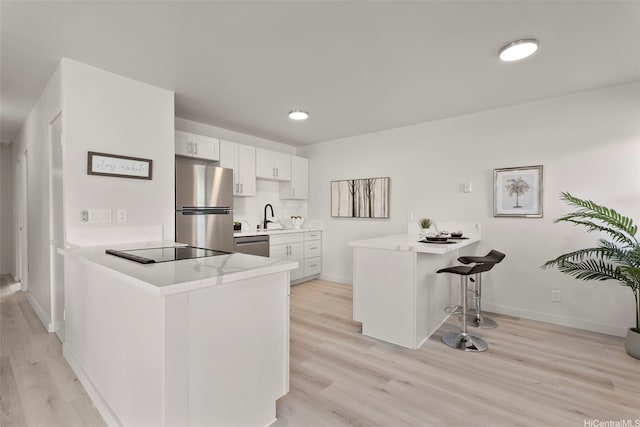 1210 Hooli Cir, Pearl City, HI 96782 - kitchen featuring stainless steel appliances, a peninsula, a breakfast bar area, light countertops, and light wood finished floors