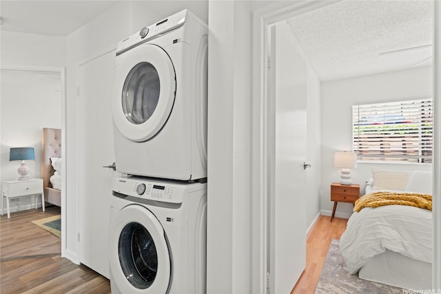 92-1132 Panana St Unit 130, Kapolei, HI 96707 - laundry area with stacked washer / dryer, light wood-style floors, a textured ceiling, and baseboards