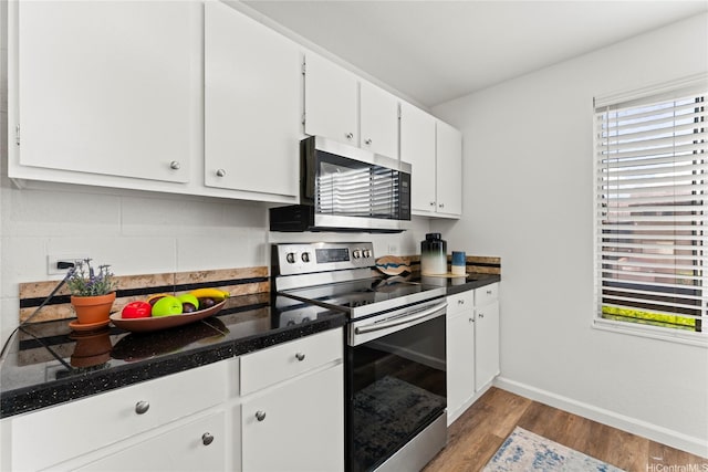 92-1132 Panana St Unit 130, Kapolei, HI 96707 - kitchen with stainless steel appliances, wood finished floors, baseboards, white cabinetry, and dark countertops