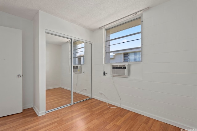 98-1042 Moanalua Rd Unit 2-303, Aiea, HI 96701 - unfurnished bedroom featuring light wood-style floors, a closet, a textured ceiling, concrete block wall, and cooling unit