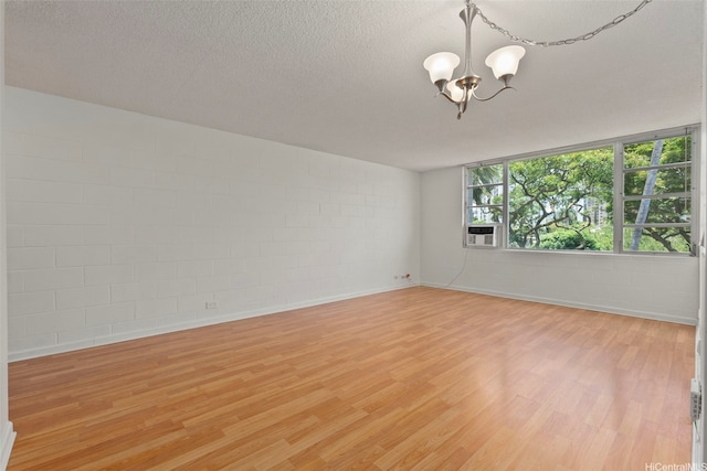 98-1042 Moanalua Rd Unit 2-303, Aiea, HI 96701 - spare room featuring a chandelier, concrete block wall, light wood-type flooring, and a textured ceiling