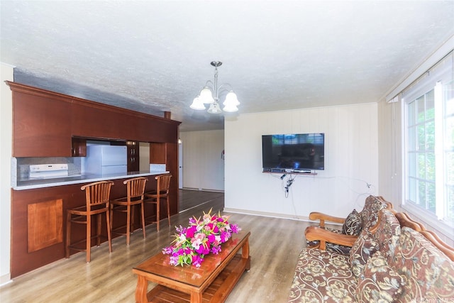 94-1190 Kahuanui St, Waipahu, HI 96797 - living area featuring wood finished floors, a chandelier, plenty of natural light, baseboards, and a textured ceiling