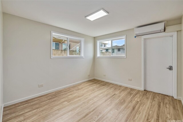 2017 Liliha St, Honolulu, HI 96817 - unfurnished bedroom with a wall unit AC, light wood-style flooring, and baseboards