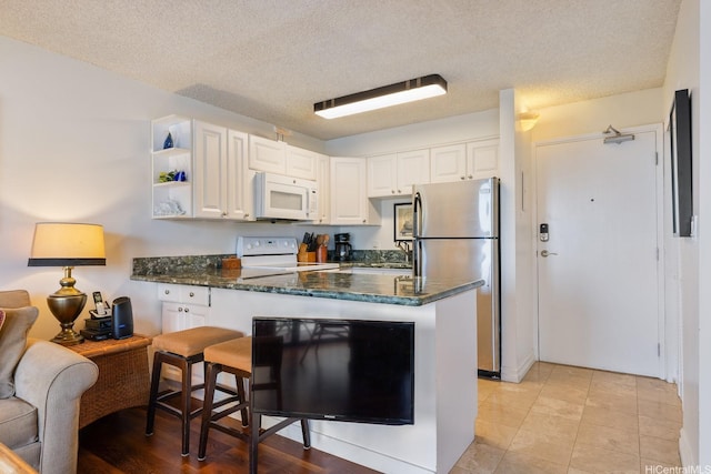 2140 Kuhio Ave Unit 1103, Nuc Honolulu, HI 96815 - kitchen featuring white microwave, electric stove, freestanding refrigerator, a sink, and white cabinets