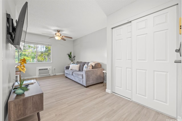 95-1015 Kaapeha St Unit 64, Mililani, HI 96789 - living room with ceiling fan, a wall mounted air conditioner, light wood-style floors, baseboards, and a textured ceiling