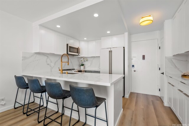 1765 Ala Moana Blvd Unit 990, Honolulu, HI 96815 - kitchen with stainless steel microwave, a peninsula, backsplash, white cabinetry, and recessed lighting