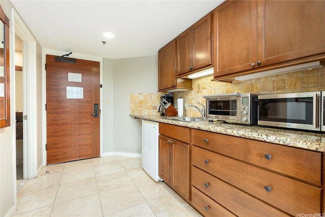 2045 Kalakaua Ave Unit 604, Honolulu, HI 96815 - kitchen featuring stainless steel microwave, dishwashing machine, brown cabinetry, backsplash, and baseboards