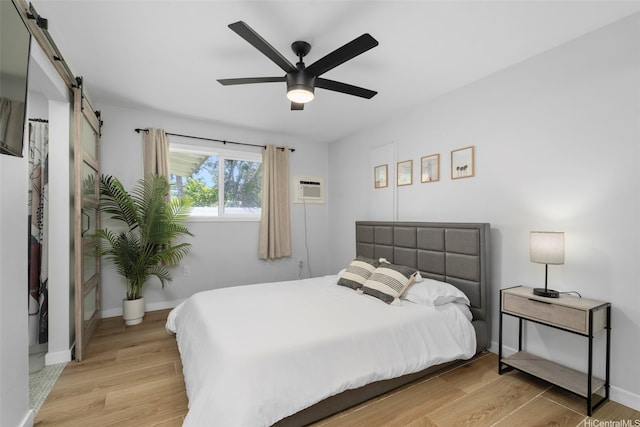 54-100 Kamehameha Hwy, Hauula, HI 96717 - bedroom featuring a barn door, light wood-style flooring, a wall unit AC, a ceiling fan, and baseboards