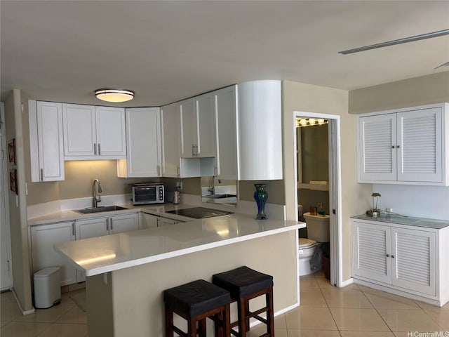 2987KALAKAUAAVENUE703 Kalakaua Ave Unit 703, Honolulu, HI 96850 - kitchen featuring a sink, light tile patterned floors, a breakfast bar area, and light countertops