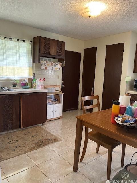 47-166 Wailehua Rd, Kaneohe, HI 96744 - kitchen with a textured ceiling, light countertops, dark brown cabinets, light tile patterned floors, and tasteful backsplash