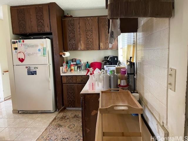 47-166 Wailehua Rd, Kaneohe, HI 96744 - kitchen with freestanding refrigerator, light countertops, light tile patterned flooring, and dark brown cabinetry