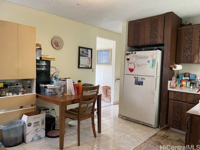 47-166 Wailehua Rd, Kaneohe, HI 96744 - kitchen with freestanding refrigerator, dark brown cabinets, light tile patterned floors, a textured ceiling, and light countertops