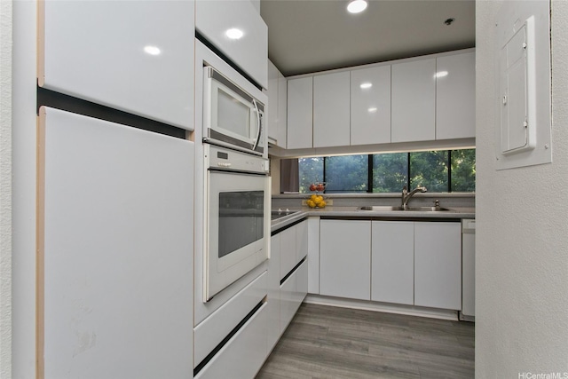 5333 Likini St Unit 110, Honolulu, HI 96818 - kitchen featuring white appliances, white cabinetry, a sink, modern cabinets, and wood finished floors